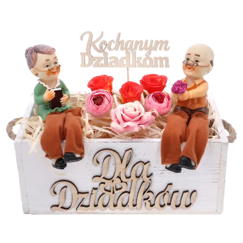 Biała skrzynka Dla Dziadków z figurkami dziadków, wypełniona sztucznymi kwiatami i topperem z napisem Kochanym Dziadkom.