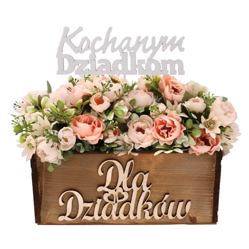 Biały topper Kochanym dziadkom umieszczony w dekoracyjnym stroiku z kwiatami w drewnianej skrzynce, stanowiący inspirację do przygotowania prezentu.