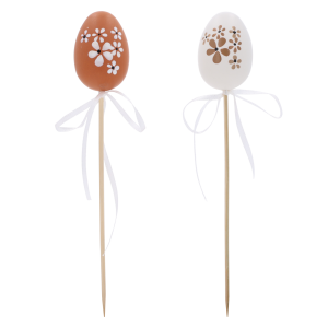 Dwie pisanki na piku o wysokości 6 cm, brązowa i biała, ozdobione kwiatowym wzorem z białą kokardką. Dekoracja idealna do wielkanocnych stroików i jaj.