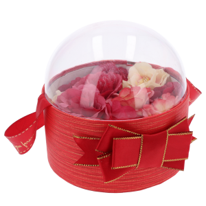 Czerwony flower box 13 cm z przezroczystą pokrywką, wewnątrz którego umieszczono kompozycję z kwiatów w czerwonych odcieniach.