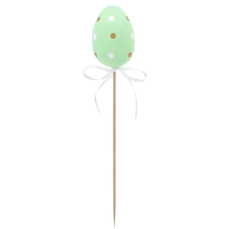 Pojedyncza zielona pisanka na piku o wysokości 6 cm. Jajko w białe i złote kropki z ozdobną kokardką, stanowiące radosny element wielkanocnej aranżacji.