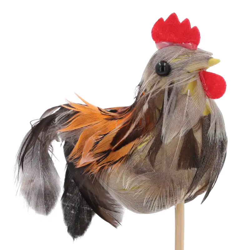 Zbliżenie na figurkę koguta na piku o wysokości 26 cm. Ozdoba z naturalnymi piórami w odcieniach brązu i pomarańczu, z czerwonym grzebieniem.