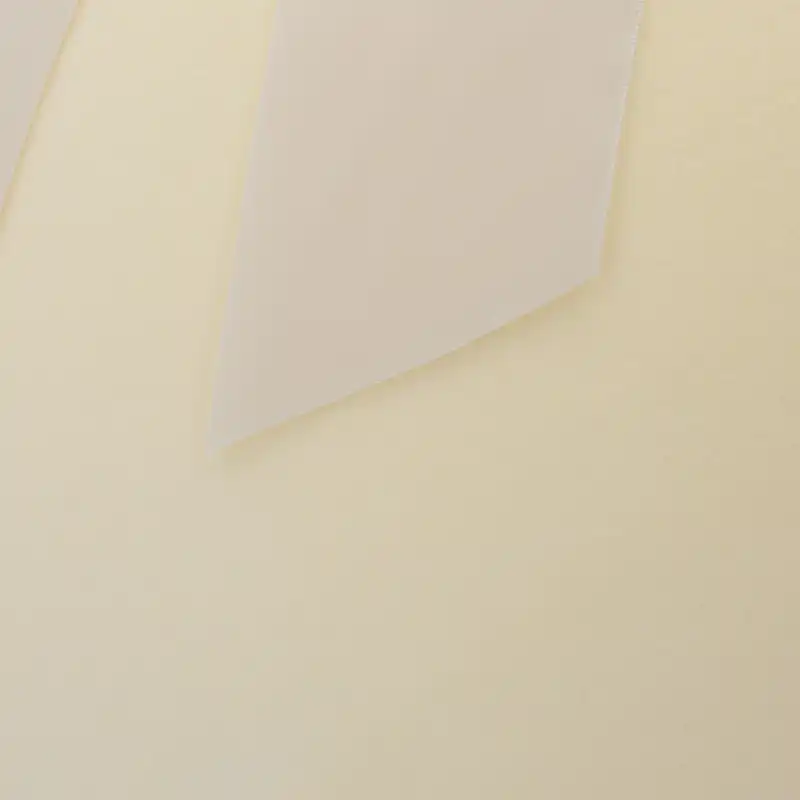 Detail powierzchni jaja wykonanego z miękkiego, kremowego weluru, z fragmentem satynowej wstążki w rogu kadru.
