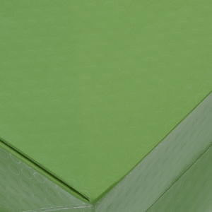Zbliżenie na strukturę materiału zielonej torebki kwiatowej. Widoczny delikatny, geometryczny wzór na powierzchni papieru.