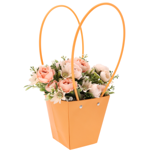 Kwiatowa aranżacja w pomarańczowej torebce o wysokości 34 cm. Ujęcie prezentujące połączenie intensywnego koloru z roślinami.