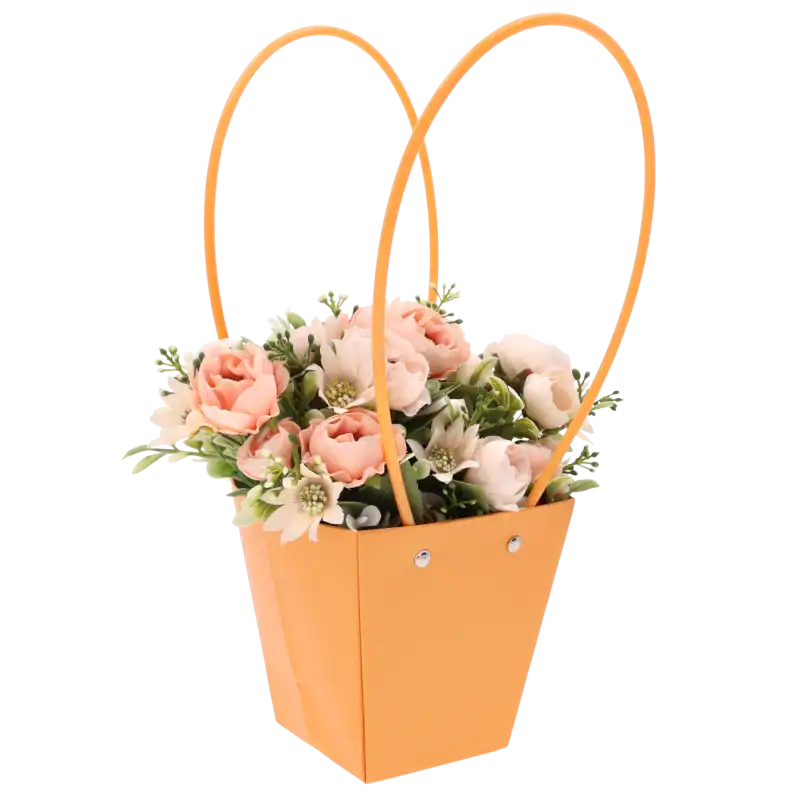 Kwiatowa aranżacja w pomarańczowej torebce o wysokości 34 cm. Ujęcie prezentujące połączenie intensywnego koloru z roślinami.