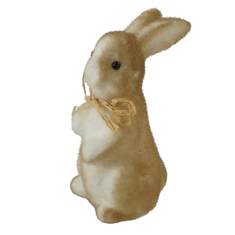Figurka brązowego zajączka wielkanocnego flokowanego, ukazana z lewego profilu. Dekoracja ze słomkową kokardą, idealna do wiosennych stroików świątecznych.
