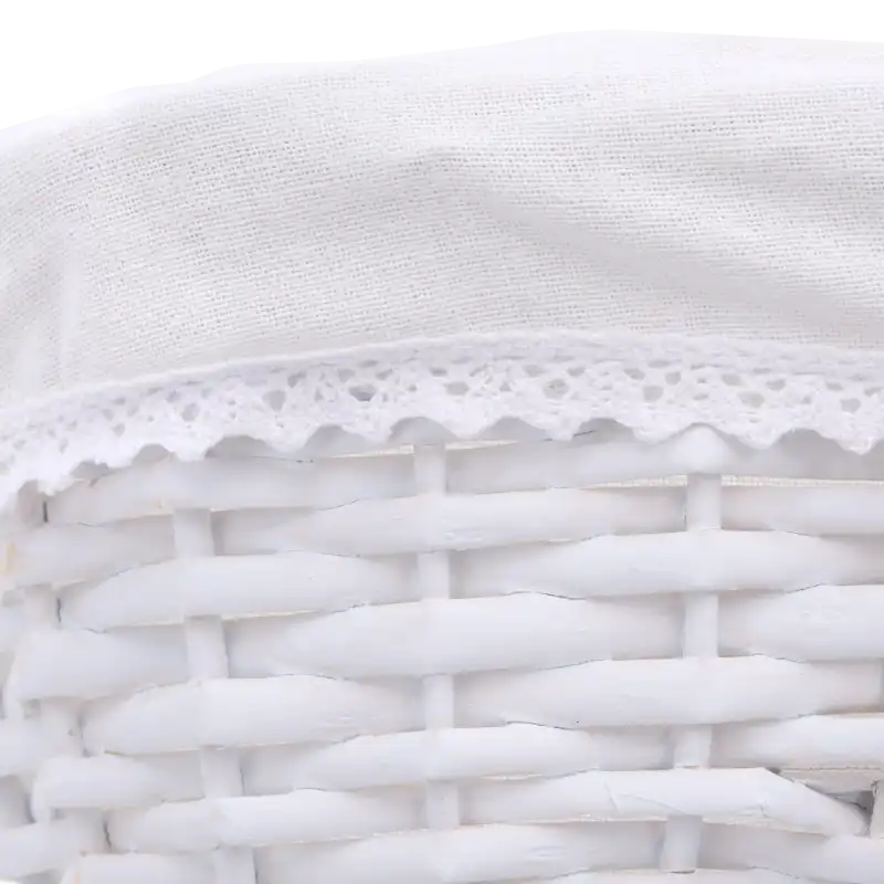 Makro zdjęcie krawędzi kosza wiklinowego, prezentujące biały materiał wykończony ozdobną ażurową koronką.