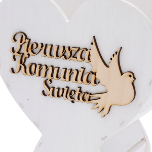 Detale grawerowanego napisu Pierwsza Komunia Święta oraz sylwetki gołębicy umieszczonej na białym drewnianym kielichu.