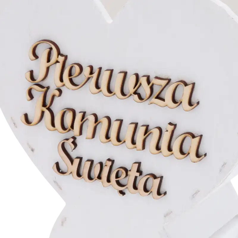 Zbliżenie na precyzyjnie wykonany grawerunek napisu Pierwsza Komunia Święta na białym drewnie.