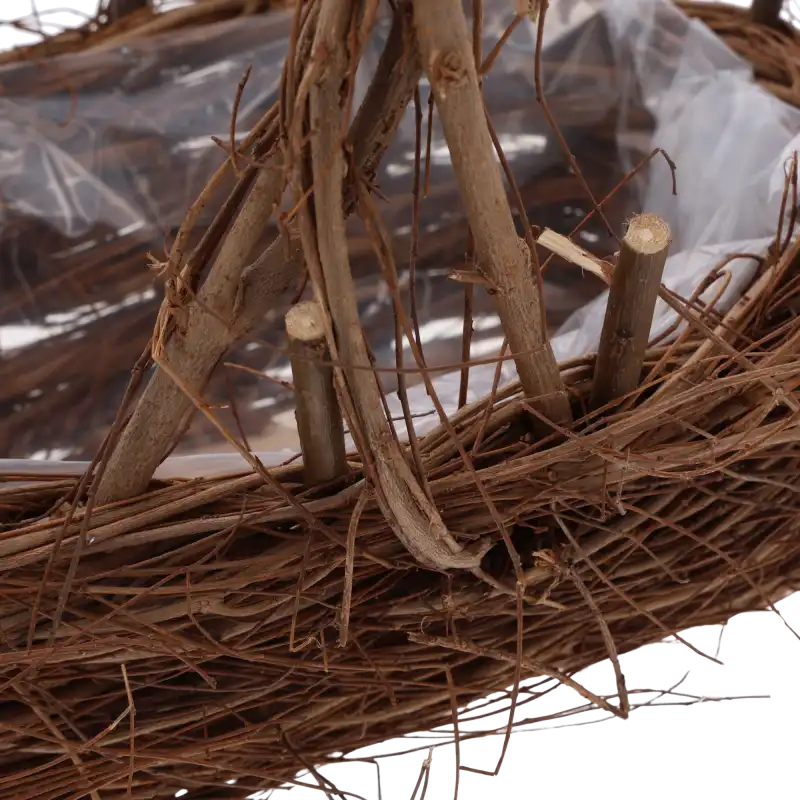Zbliżenie na konstrukcję z naturalnych gałązek oraz sposób mocowania rączki w koszu do kompozycji roślinnych.