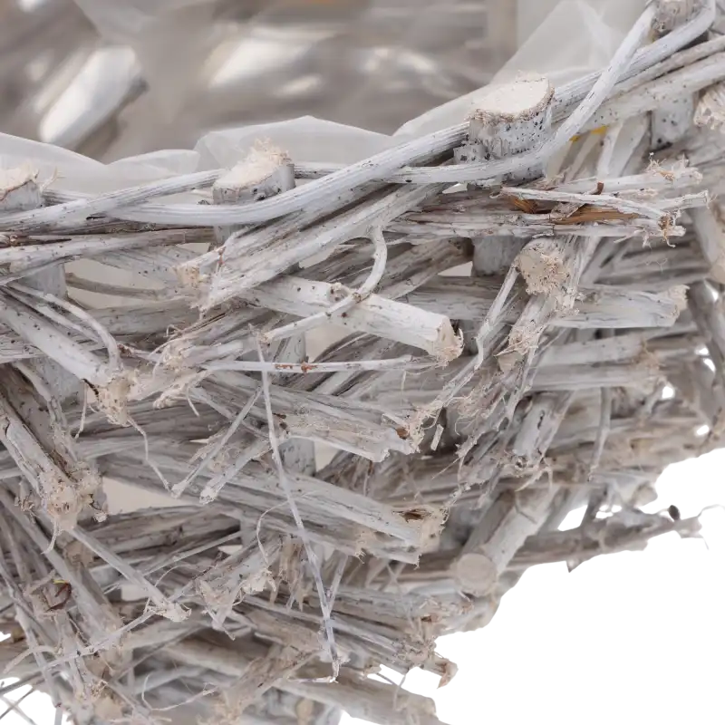 Zbliżenie na detale drewnianej przeplatanki. Widoczna tekstura naturalnych gałązek w szarym odcieniu oraz krawędź folii.