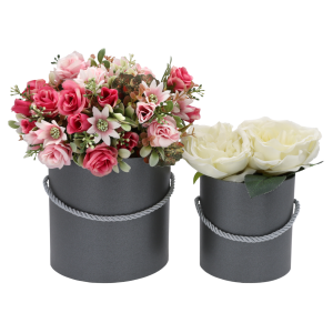 Dwa szare flower boxy wypełnione sztucznymi kwiatami w odcieniach różu i bieli. Dekoracyjna kompozycja w perłowych pudełkach.