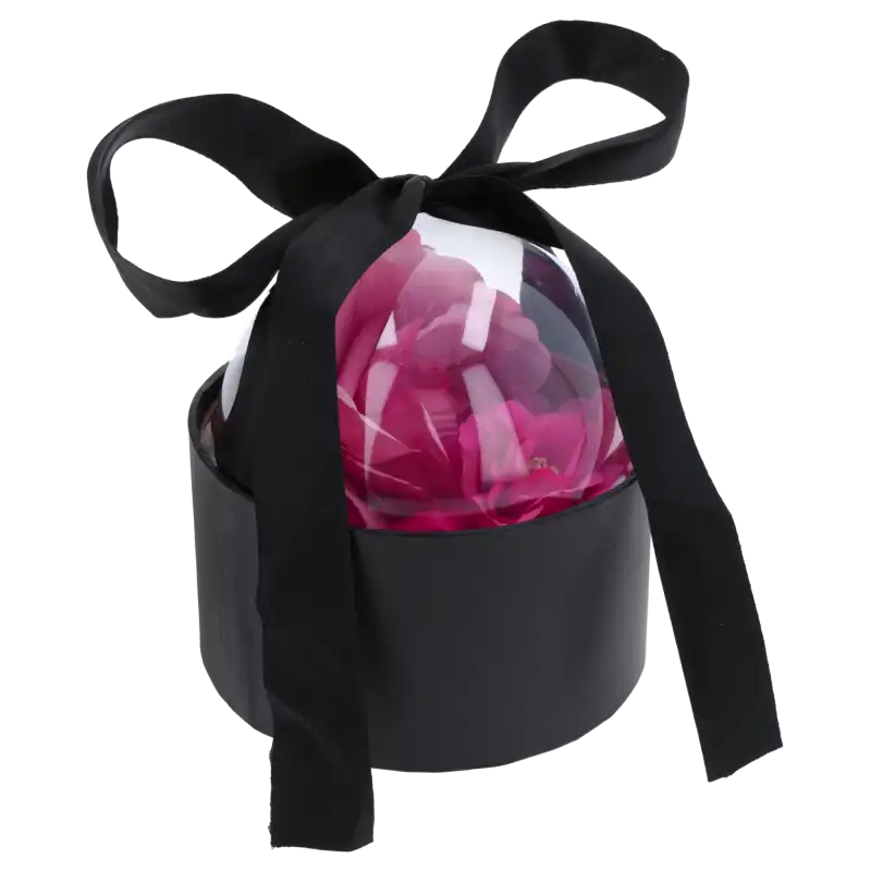 Czarny flower box o średnicy 13 cm z przezroczystą półkulą wypełnioną różowymi kwiatami i czarną kokardą.