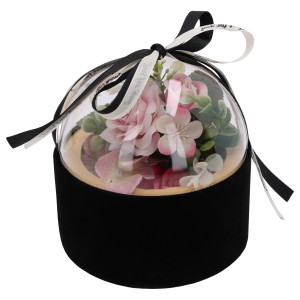 Czarny welurowy flower box z przezroczystą górą, wewnątrz którego umieszczono kompozycję z różowych kwiatów. Półkula zwieńczona dekoracyjną kokardą.