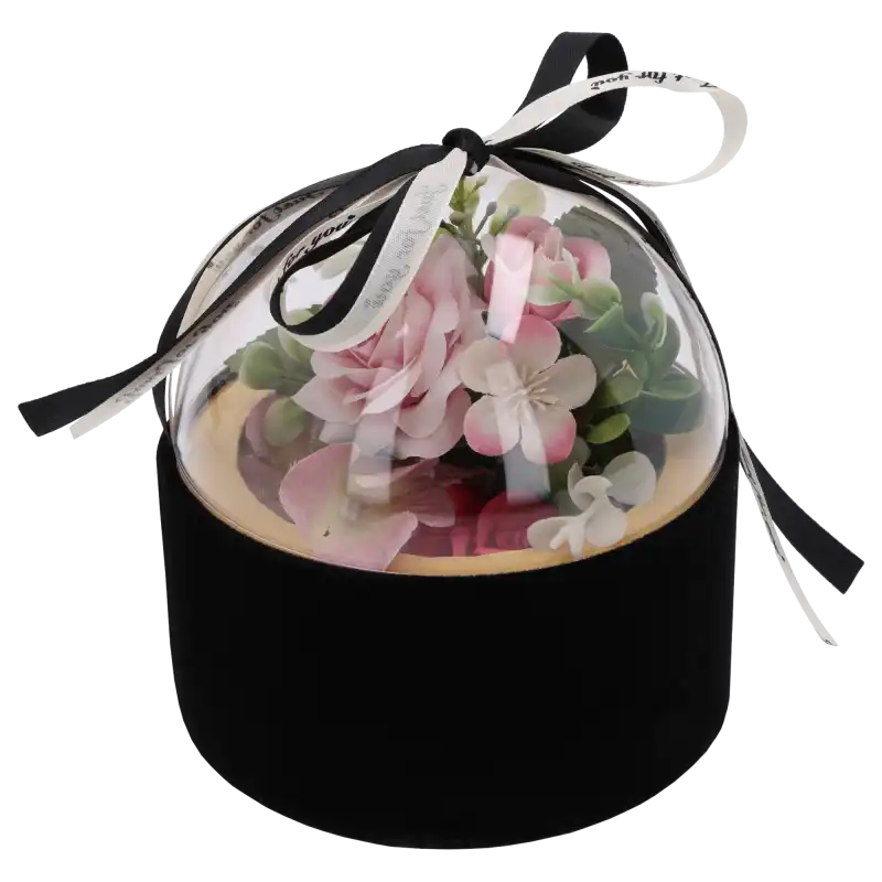 Czarny welurowy flower box z przezroczystą górą, wewnątrz którego umieszczono kompozycję z różowych kwiatów. Półkula zwieńczona dekoracyjną kokardą.