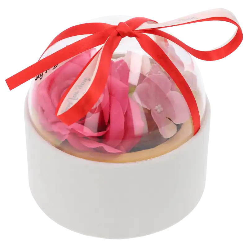 Welurowy flower box w kolorze białym wypełniony kwiatami, zamknięty przezroczystą półkulą. Całość przewiązana jest ozdobną wstążką.