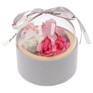 Welurowy flower box w kolorze szarym wypełniony różowymi i białymi kwiatami, zamknięty przezroczystą półkulistą pokrywką.