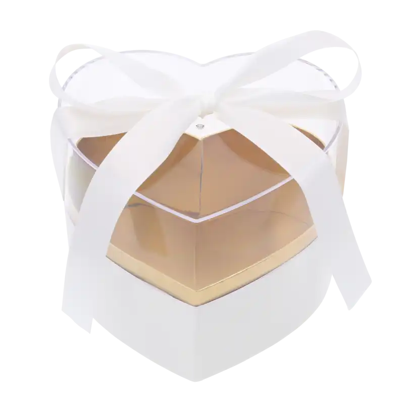 Biały flower box w kształcie serca z przezroczystą pokrywką i złotym wnętrzem. Eleganckie opakowanie na kwiaty i prezenty komunijne, ozdobione wstążką.