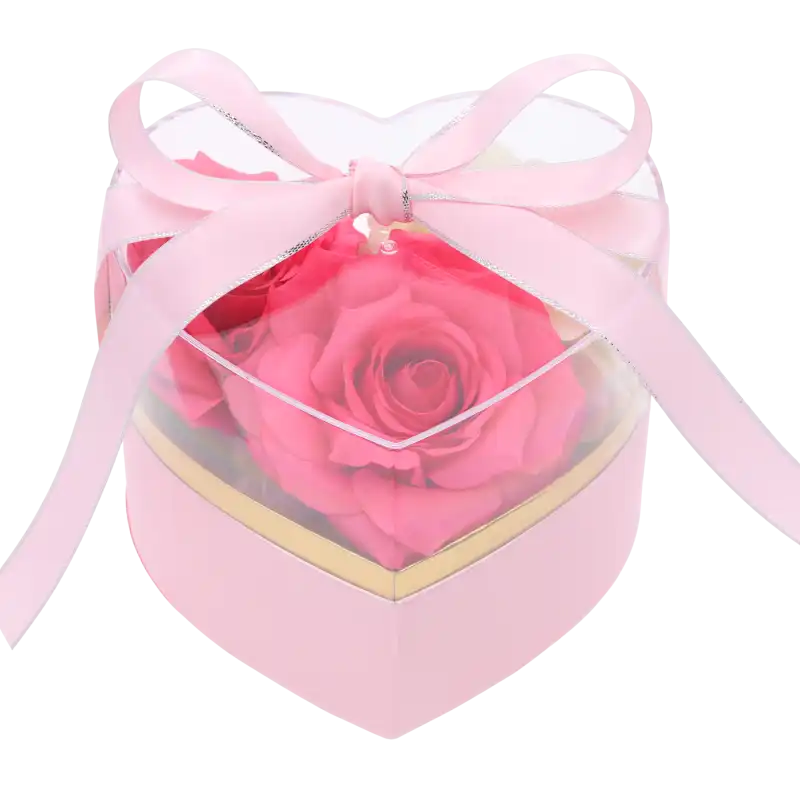Różowy flower box z przezroczystą pokrywką, wewnątrz wypełniony kompozycją z różowych kwiatów. Elegancka dekoracja.