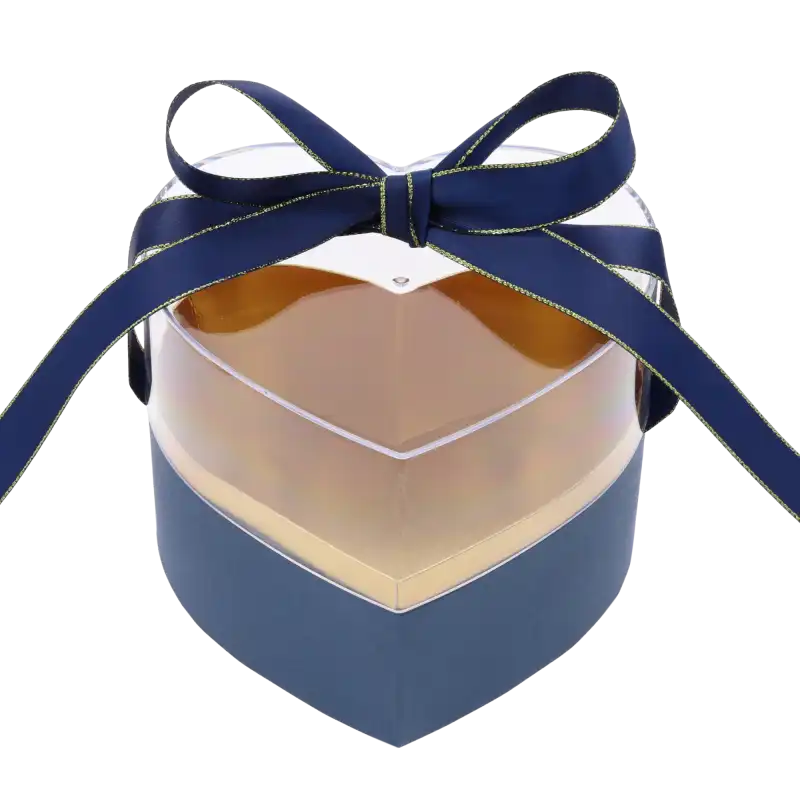 Granatowy flower box w kształcie serca z przezroczystą pokrywką, ozdobiony elegancką wstążką, prezentujący luksusowe złote wnętrze pudełka prezentowego.