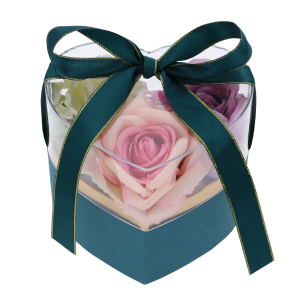 Przezroczysty flower box z wypełnieniem w postaci sztucznych róż w odcieniach różu i bieli. Pudełko zamknięte dekoracyjną kokardą.