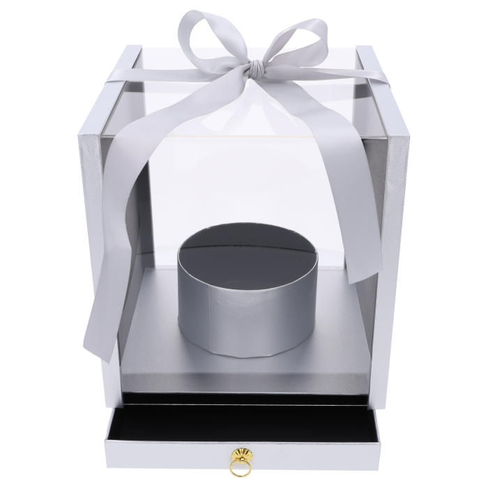 Srebrny flower box o wymiarach 25x25 cm z przezroczystymi ściankami, ozdobną kokardą i wysuwaną szufladą. Pudełko posiada okrągłą osłonkę na kwiaty.