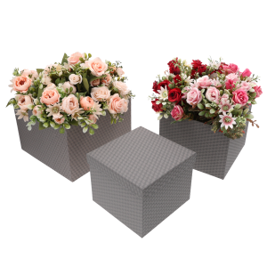 Dwa szare kwadratowe flower boxy wypełnione sztucznymi różami w odcieniach różu i czerwieni, obok stoi puste pudełko z zamkniętą pokrywką.