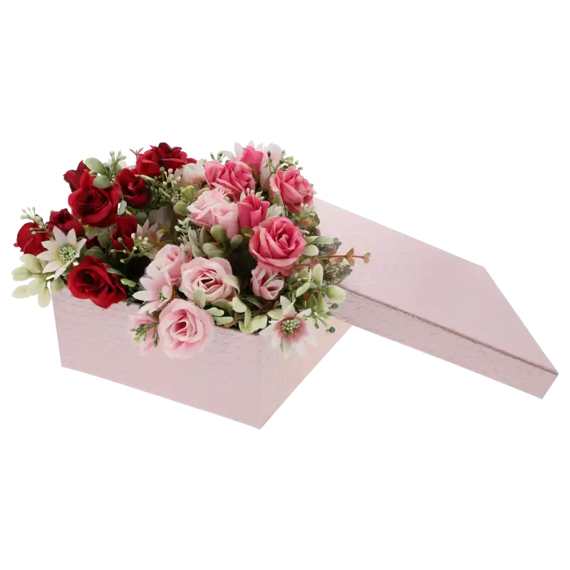 Różowy flower box wypełniony kompozycją kwiatową z czerwonych i różowych sztucznych róż, obok leży zdjęta pokrywka.