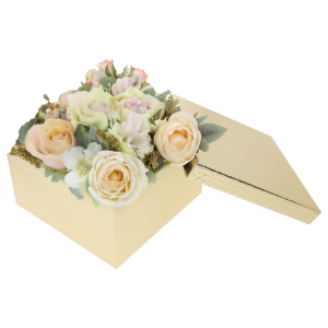 Złoty kwadratowy flower box z kompozycją kwiatową w pastelowych odcieniach. Obok pudełka leży dopasowana pokrywka, podkreślająca funkcjonalność zestawu.