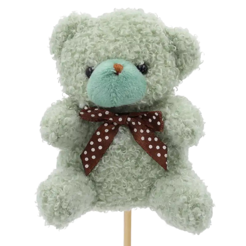 Zbliżenie na pluszowego zielonego misia na piku o wysokości 35 cm, ozdobionego elegancką brązową kokardą w białe kropki. Idealny topper do bukietów.