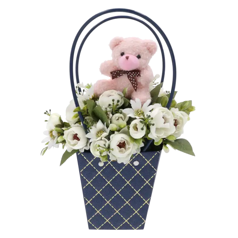 Jasnoróżowy miś na piku umieszczony w dekoracyjnym flower boxie z białymi kwiatami, gotowa kompozycja.