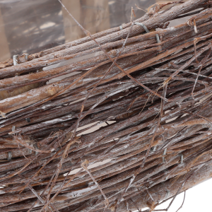 Zbliżenie na fakturę drewnianych gałązek tworzących ścianki kosza, ukazujące naturalny materiał wykonania.