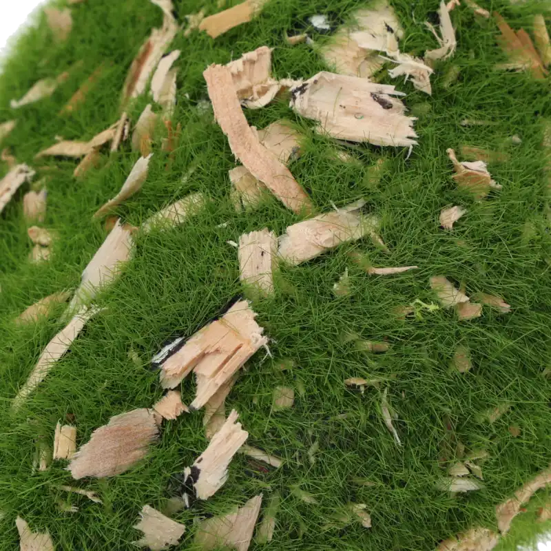 Zbliżenie na powierzchnię kamienia dekoracyjnego, ukazujące strukturę mchu oraz przyklejone fragmenty naturalnej kory.