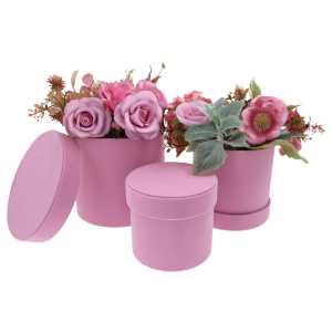 Zestaw trzech różowych flower boxów, z których dwa wypełnione są kwiatami. Jedna pokrywka leży obok pudełka na podłożu.
