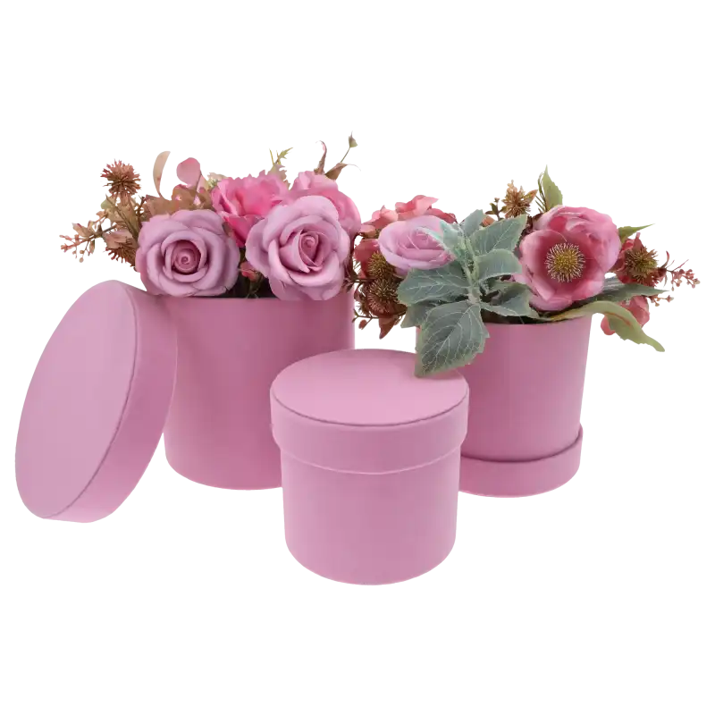 Zestaw trzech różowych flower boxów, z których dwa wypełnione są kwiatami. Jedna pokrywka leży obok pudełka na podłożu.