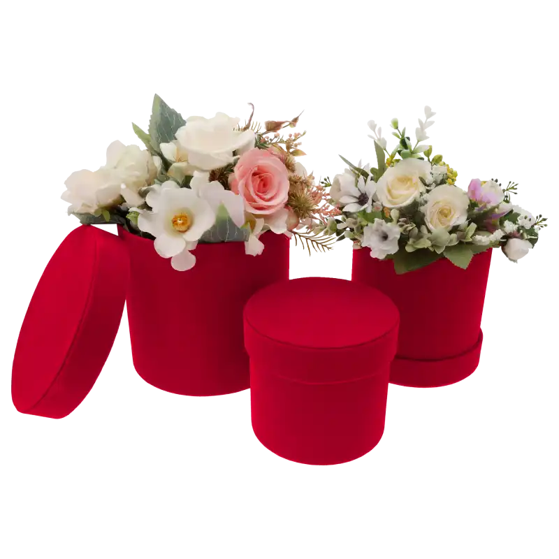Dwa czerwone welurowe flower boxy z kompozycjami kwiatowymi oraz trzecie mniejsze puste pudełko z pokrywką z przodu.