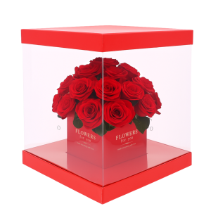 Czerwony kwadratowy flower box 25x25 cm wypełniony żywymi różami. Przezroczyste boki pozwalają wyeksponować rośliny, a dyskretne otwory zapewniają im dostęp do powietrza.