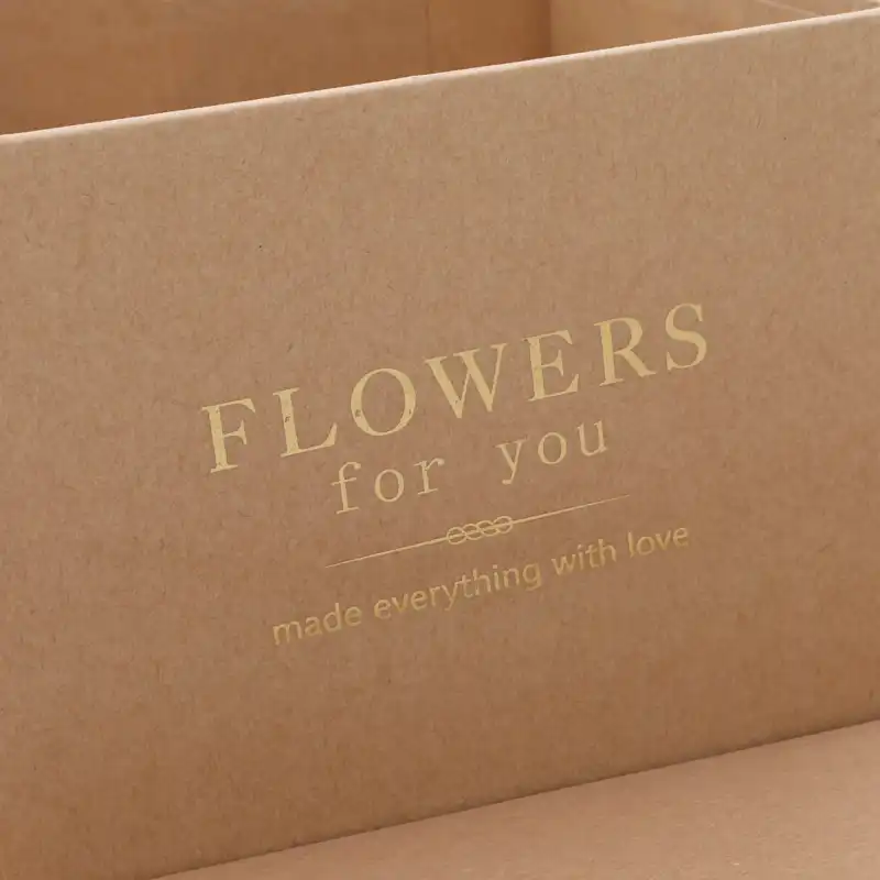 Zbliżenie na nadruk na kraftowym pudełku z napisem Flowers for you wykonany w złotym kolorze.