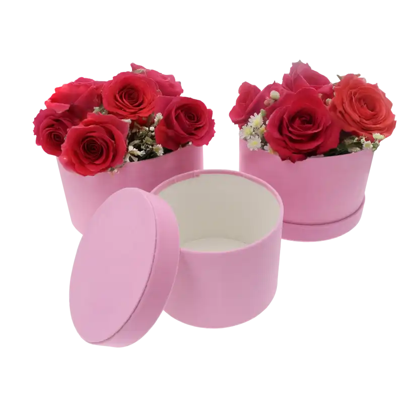 Różowe welurowe flowerboxy z kompozycjami z żywych czerwonych róż. Pudełka stanowią bazę dla florystyki.