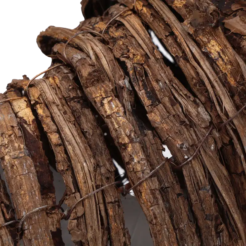 Detail konstrukcji wieńca z kory z widocznymi pozłacanymi akcentami na naturalnej powierzchni drewna.