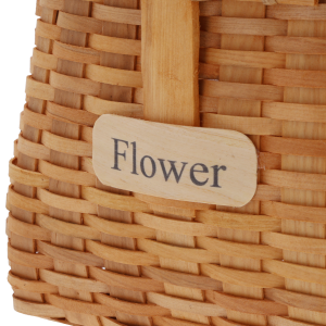 Zbliżenie na drewnianą tabliczkę z napisem Flower umieszczoną na froncie kosza dekoracyjnego.