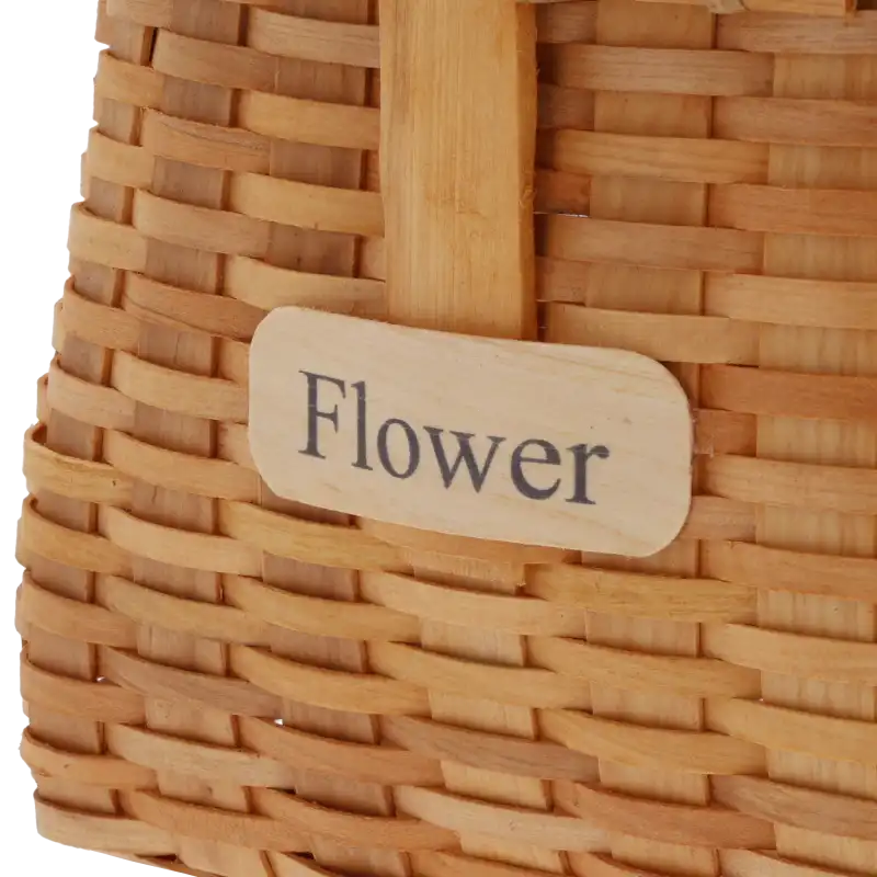 Zbliżenie na drewnianą tabliczkę z napisem Flower umieszczoną na froncie kosza dekoracyjnego.
