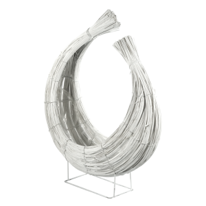 Rattanowa osłonka w kolorze białym ustawiona na metalowej podstawie. Prezentuje unikalny design z pasów rattanu oraz widoczną folię zabezpieczającą wnętrze.