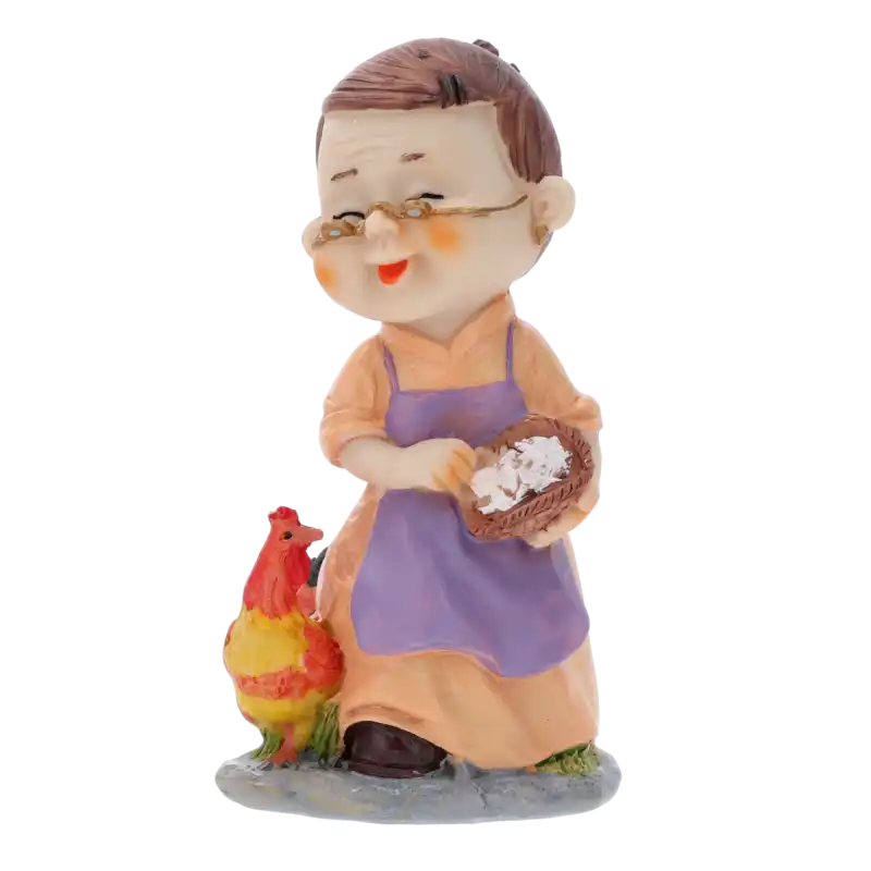 Zbliżenie na figurkę babci w okularach, która w rękach trzyma mały koszyk. Obok niej stoi kolorowa kura. Postać ma radosny wyraz twarzy i jest ubrana w fartuszek. Dekoracja na jasnym tle.