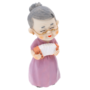 Ujęcie z boku dekoracyjnej figurki babci z harmonią. Widać detale stroju oraz okularów postaci o wysokości 15 cm.