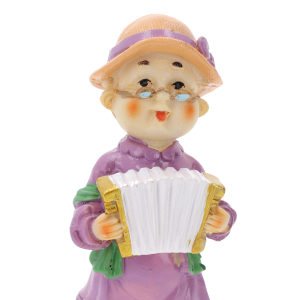 Zbliżenie na twarz figurki babci z harmonią. Widoczne detale okularów, kapelusza oraz instrumentu muzycznego. Ujęcie typu portretowego na białym tle.