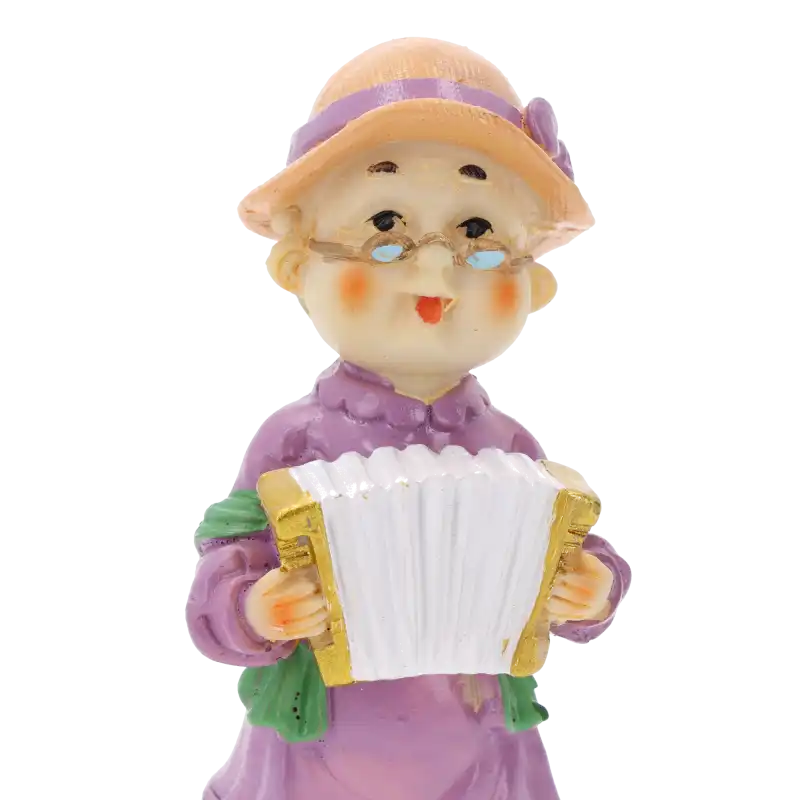Zbliżenie na twarz figurki babci z harmonią. Widoczne detale okularów, kapelusza oraz instrumentu muzycznego. Ujęcie typu portretowego na białym tle.