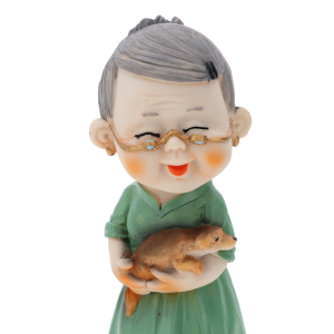Zbliżenie na figurkę babci o wysokości 15 cm. Postać w zielonej sukience trzymająca małe zwierzątko, wykonana z lekkiego tworzywa.