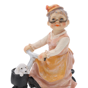 Zbliżenie na górną część figurki: babcię jadącą na rowerze. Widać szczegółowo wykonaną twarz, okulary oraz pieska w koszyku.